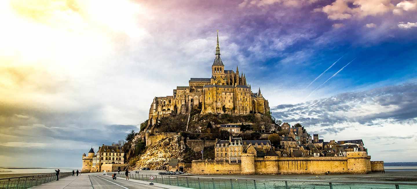 Breathtaking view of Mont St Michel Island with its historic church and abbey against a dramatic sky in Normandy, France, a popular tourist destination.