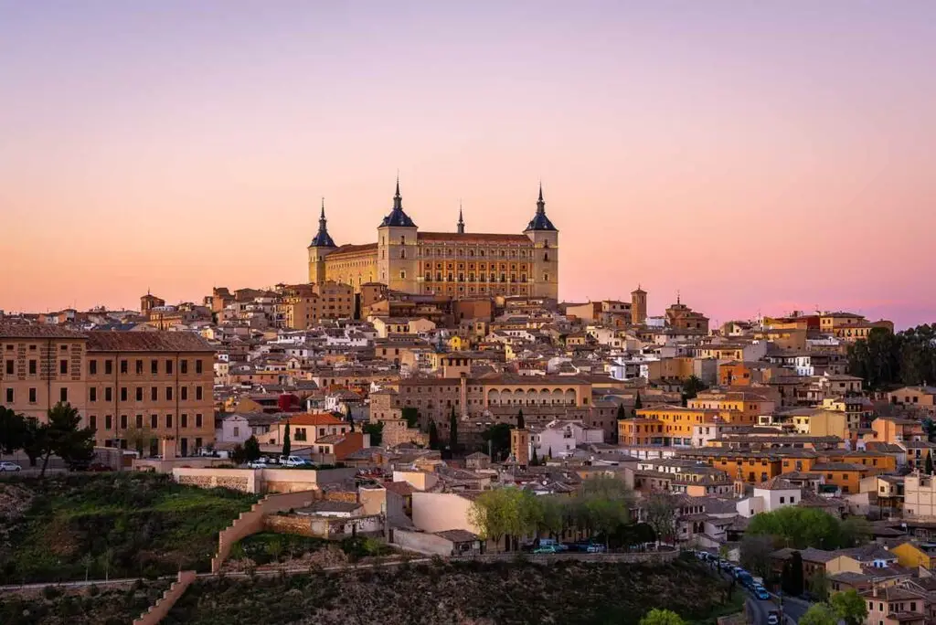 Panoramic view of Toledo, Spain at sunset featuring Alcazar Castle and historic cityscape in Castilla-La Mancha