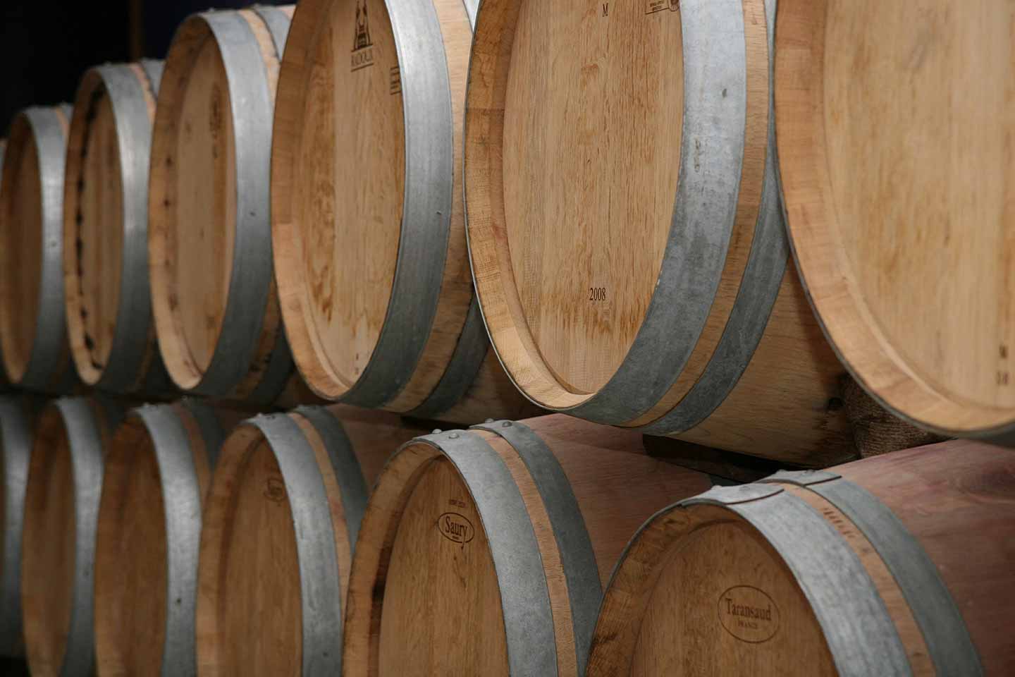 wine barrels in rows in a cellar at a winery in bordeaux.