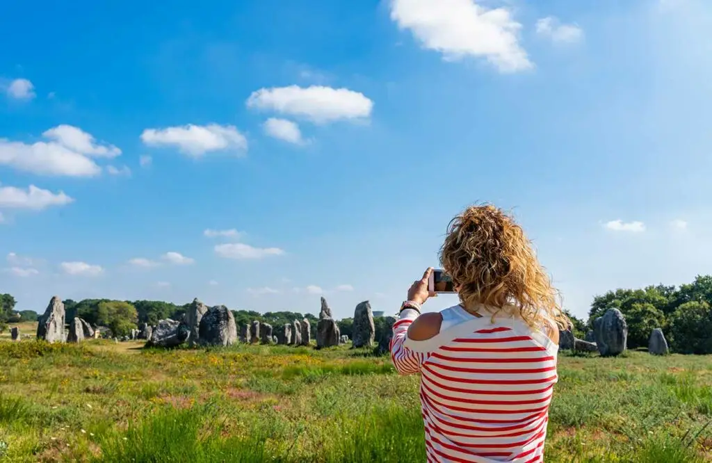 Best of Brittany tour, woman taking pictures of standing stones in Carnac France.