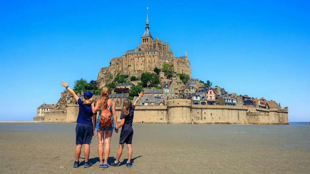 family of mother and two daughters posing outside of Le Mont Saint Michel - Normandy