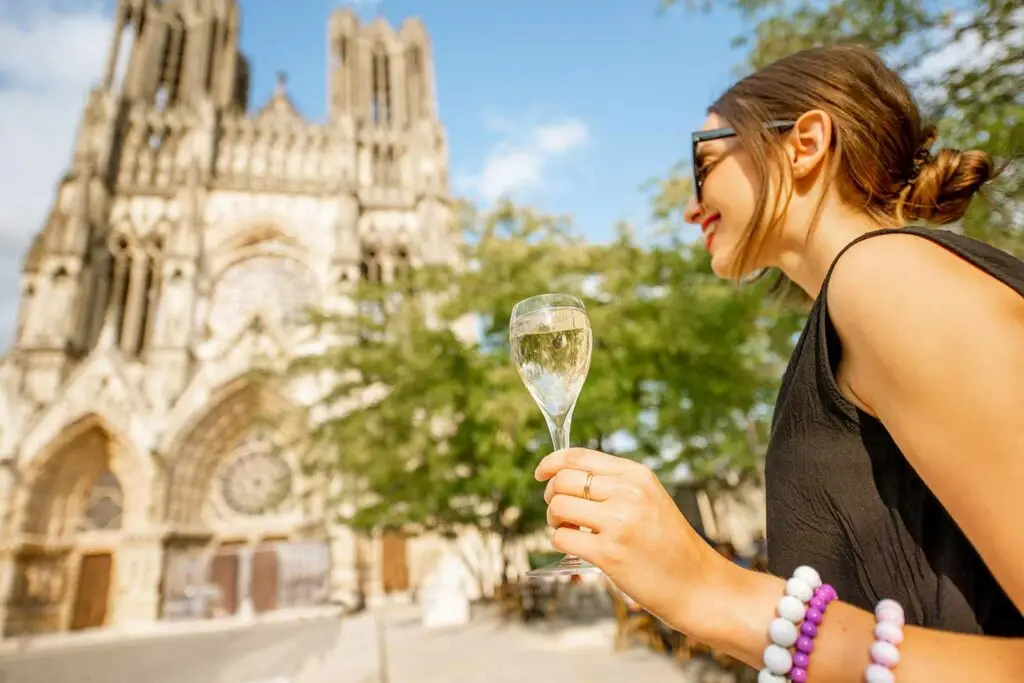 woman with glass of wine standing outside champagne, Reims, Cathedral on a private tour