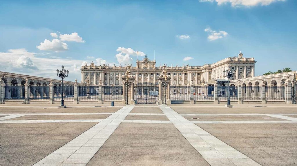 View of the Royal Palace of Madrid, Spain, showcasing its magnificent facade and intricate architectural details under a clear blue sky.