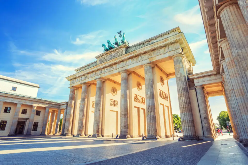 Sunlit view of the Brandenburg Gate in Berlin, Germany, showcasing its iconic neoclassical architecture and Quadriga sculpture on a clear day.