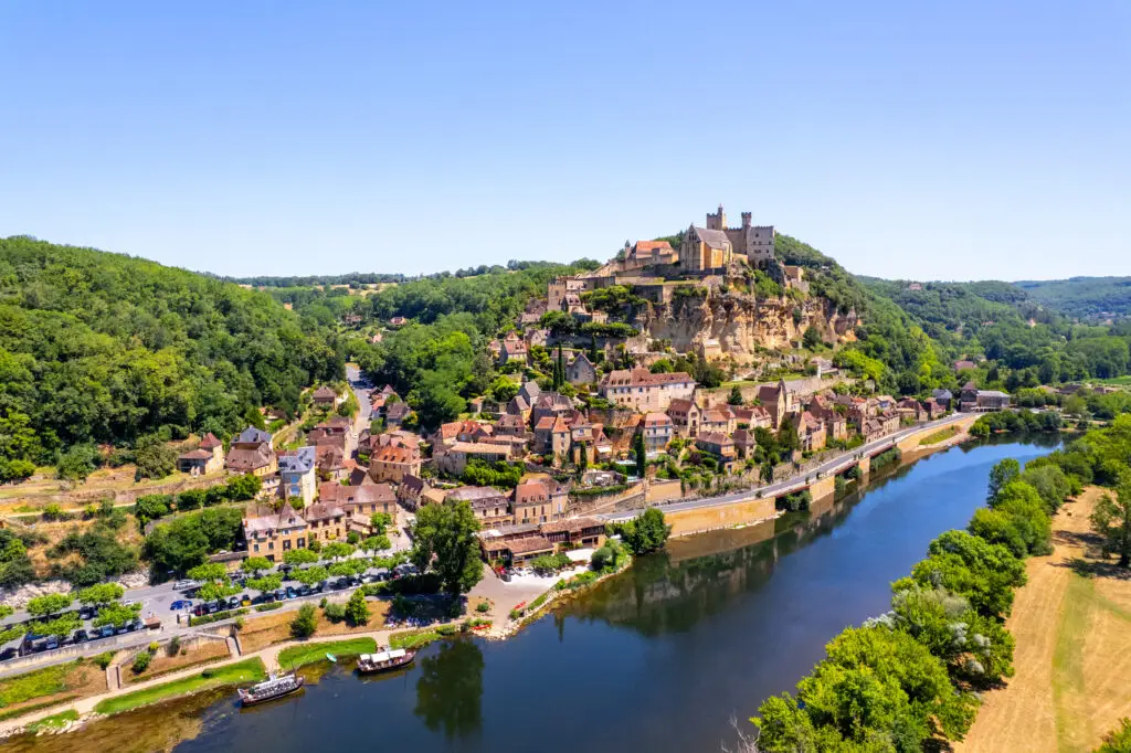 Aerial view of Chateau de Beynac and Cazenac Village along the Dordogne River in France, showcasing the historic architecture and scenic river landscape.