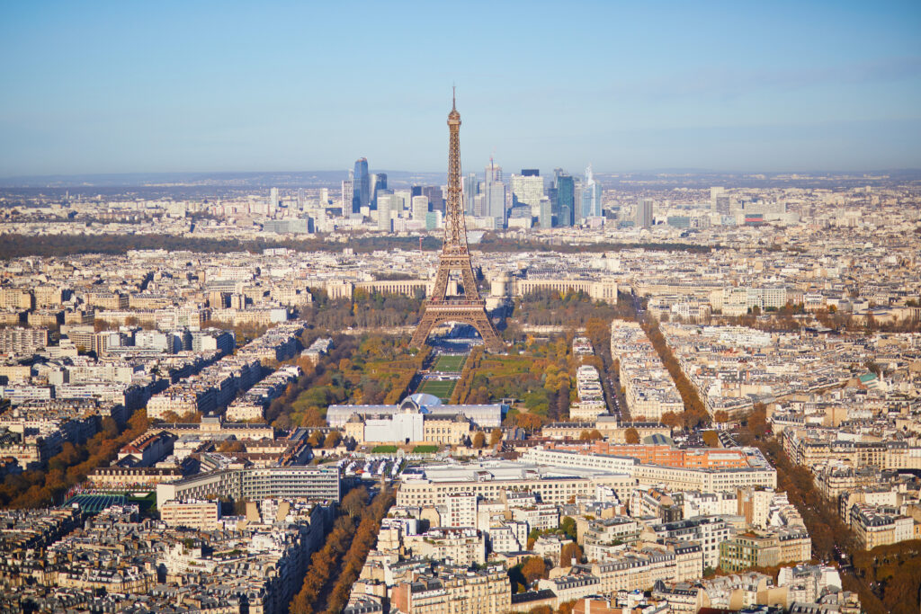 Aerial view of the Eiffel Tower and Paris skyline from Montparnasse Tower, showcasing the city's dense architecture and distant urban landscapes.