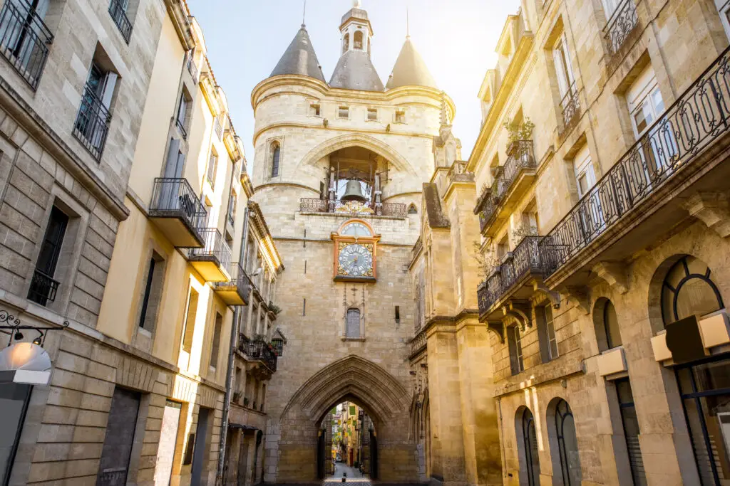 Historic Porte Cailhau gate in Bordeaux, France, with distinctive medieval architecture and street view bathed in sunlight.