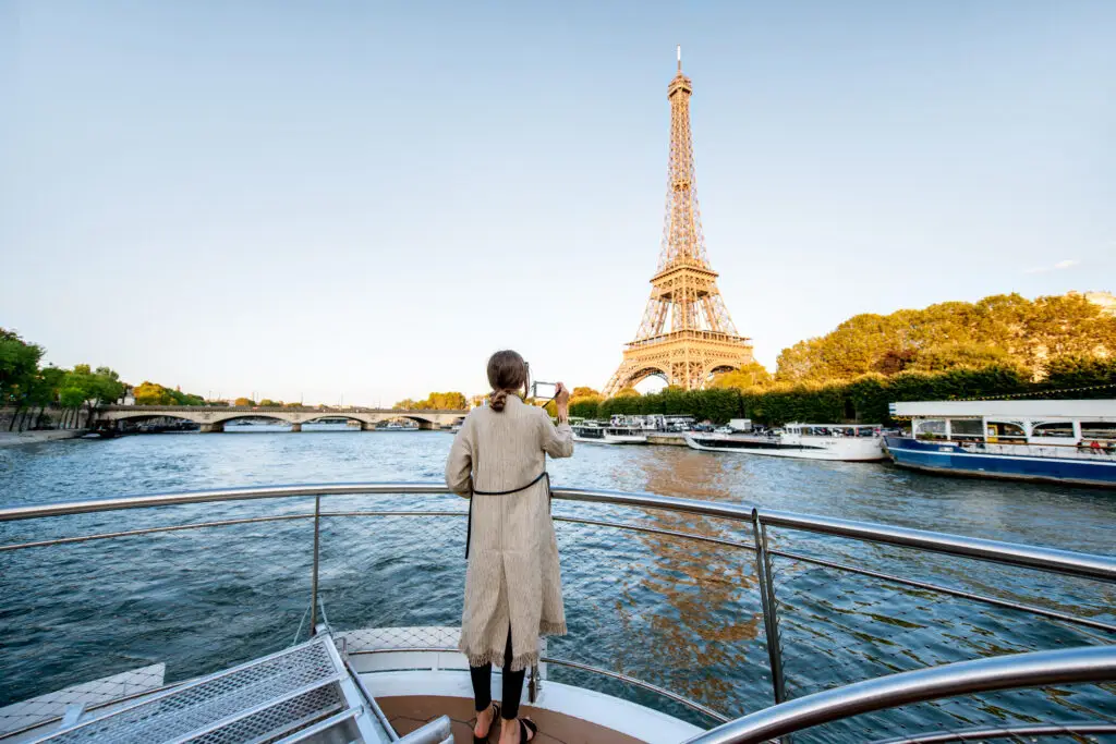 Woman on boat tour capturing breathtaking view of the Eiffel Tower in Paris, perfect for romantic and scenic France tourism experiences.