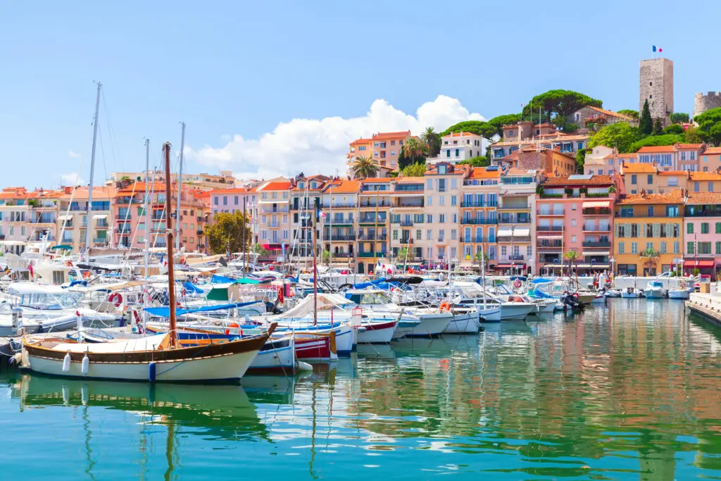 Colorful Cannes marina with anchored boats and cultural architecture, reflecting a clear summer day in France.