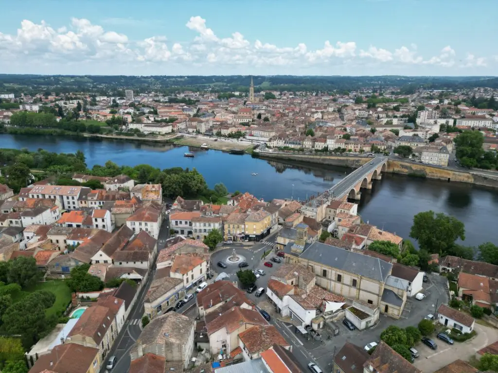Aerial view of Bergerac, showing the Dordogne River and historic road bridge, highlighting the picturesque townscape and verdant surroundings in France.