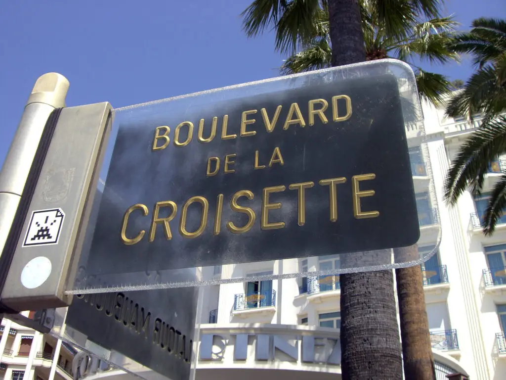 Signpost of Boulevard de la Croisette in Cannes, France, framed by palm trees and blue sky, highlighting a popular tourist destination.
