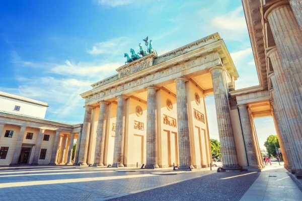 Sunlit view of the Brandenburg Gate in Berlin, Germany, showcasing its iconic neoclassical architecture and Quadriga sculpture on a clear day.