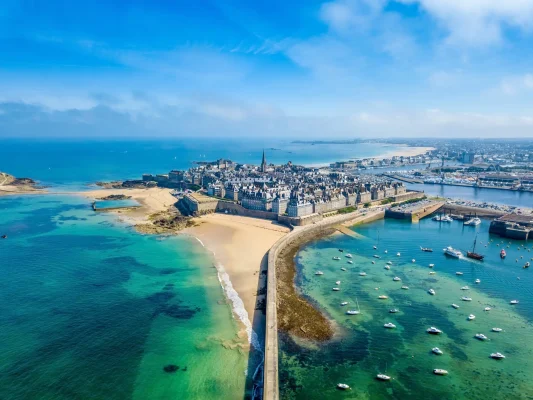 Aerial view of Saint Malo, France showcasing the historic walled city with serene beaches and azure waters, ideal for luxury France tours.