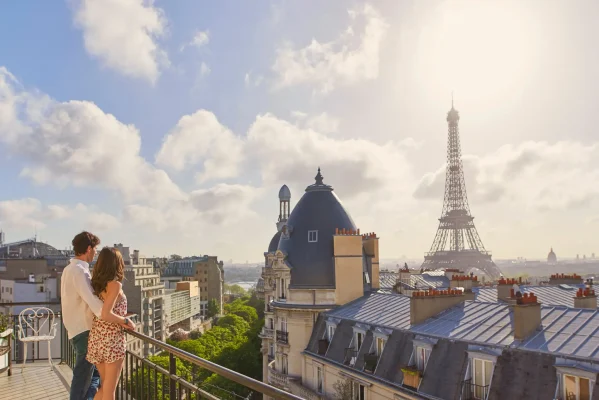 Couple enjoying a scenic view of the Eiffel Tower from a balcony in Paris, capturing the essence of romantic French tourism