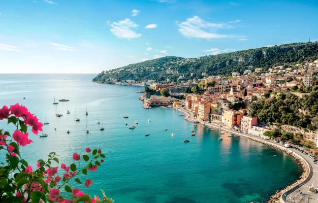 Panoramic view of Villefranche-sur-Mer, a charming coastal town located between Nice and Monaco on the French Riviera, featuring azure waters, moored boats, and vibrant architecture.
