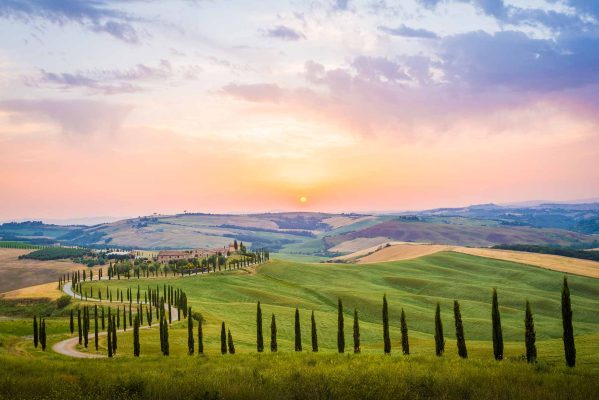 Scenic sunset over the twisty cypress road and rolling hills of Val d'Orcia, Tuscany, Italy